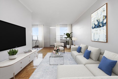 A living room with a white couch, a black television, and a painting on the wall.