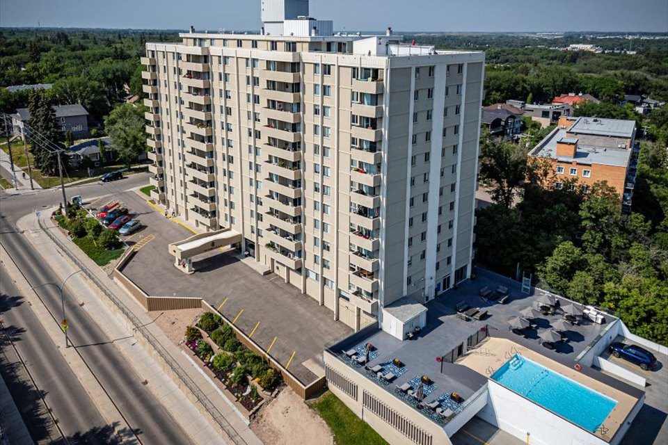 A tall white building with a pool in front.