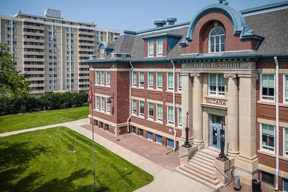 the front of a brick building with a green lawn and an apartment building