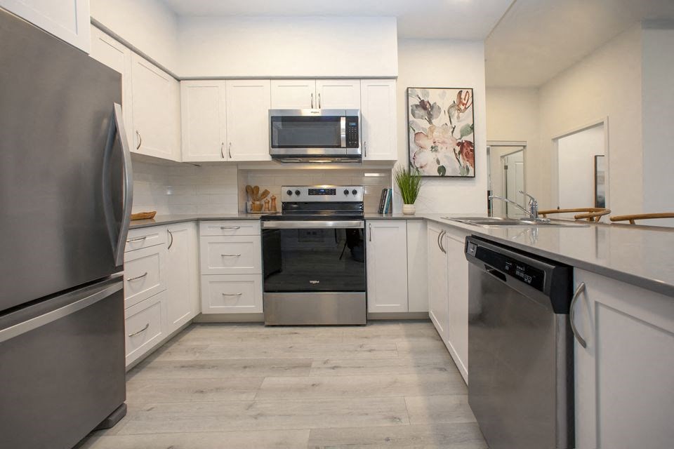 Kitchen with white designer cabinetry and stainless steel fridge, stove, over-the-range microwave and dishwasher at Bayfield Tower Apartments in Barrie, ON