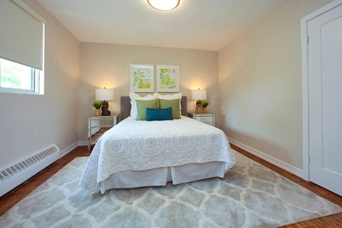 A bedroom with a large bed and a rug on the floor.