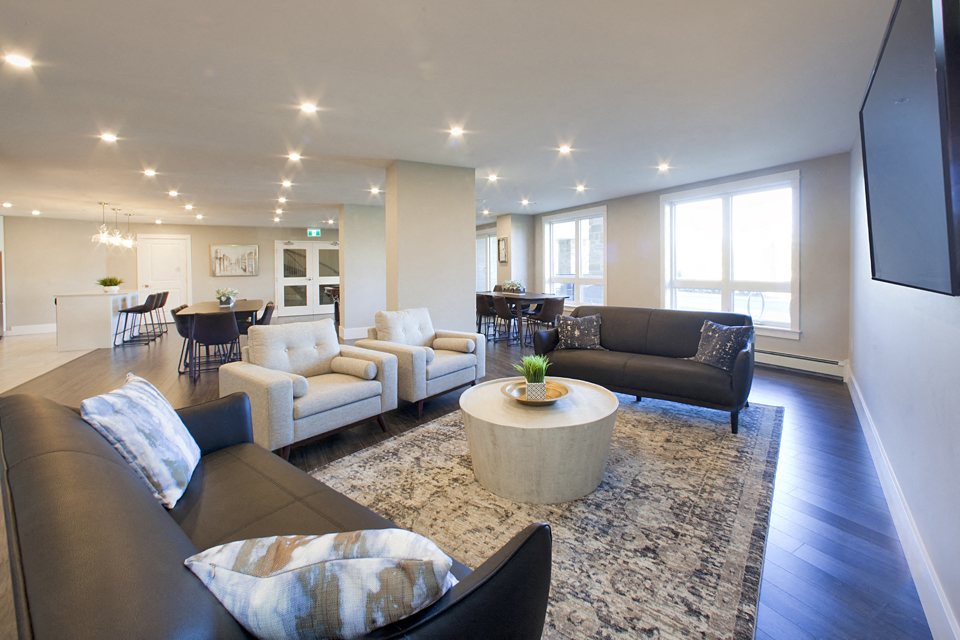 Amesbury Gate Social room with two brown couches and two cream coloured chairs surrounding a wooden table in Bedford, NS