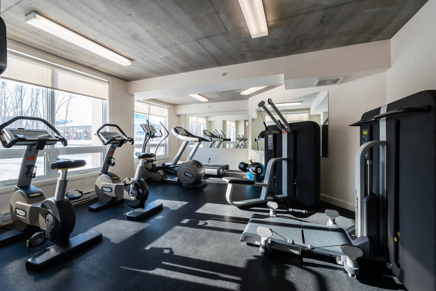 Brightly lit, fully equipped fitness centre at Axial Towers apartment in Laval, Quebec