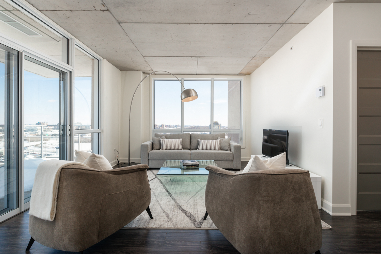Spacious modern living room with large windows and luxury flooring at Axial Towers apartment in Laval, Quebec