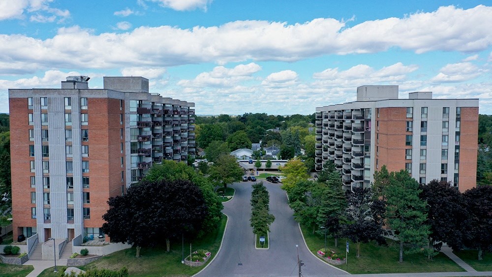 a city street with two apartment buildings on either side and trees in the background