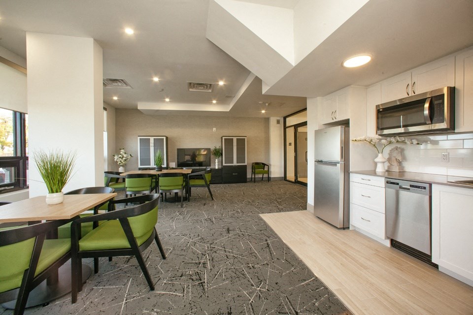 Social room with kitchenette, tables and chairs and a flat-screen TV at Bayfield Tower Apartments in Barrie, ON