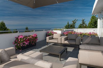 Bayview Gardens Apartments outdoor patio featuring lounge seating and flower planters in White Rock, BC - Photo Gallery 9
