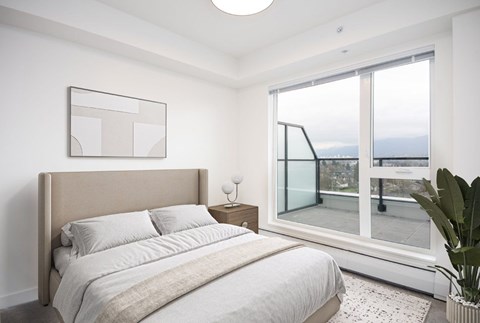 A bedroom with a large bed and a view of the ocean through a glass door at 388 Kaslo East Village.