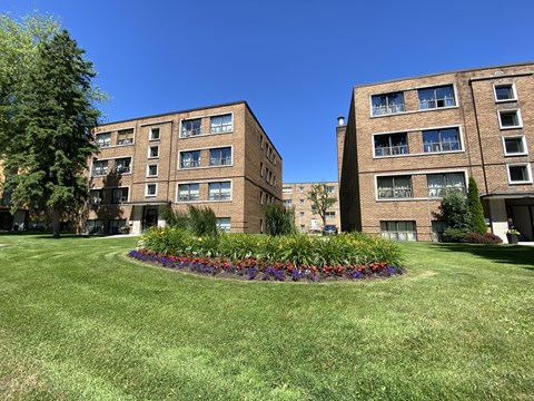 a flower bed in the middle of a lawn between two apartment buildings