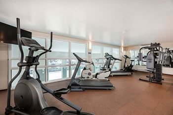 Fitness facility with cardio and weight equipment overlooking indoor pool at Bourg du Village in Ste Therese Quebec