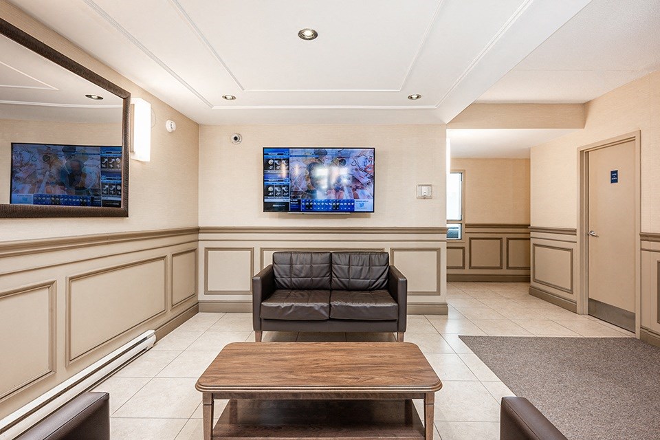 Bourg du Village lobby with seating area and large screen television in Sainte Therese, QC