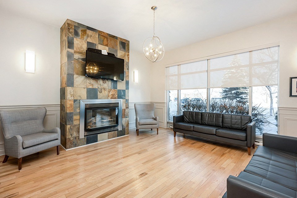 Bourg du Village social room showing seating area, fireplace and large screen TV in Sainte Therese, QC