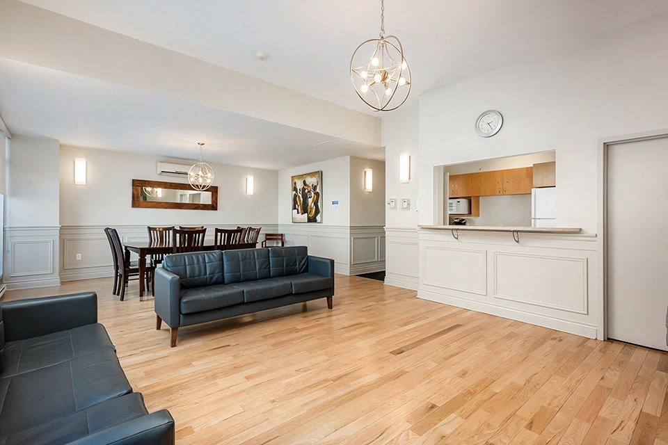 Bourg du Village social room showing seating area with kitchenette and dining area in background in Sainte Therese, QC