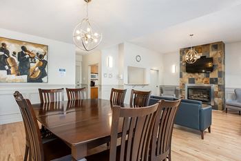 Resident's lounge at Bourg du Village in Ste Therese Quebec, showing fireplace, large screen TV, kitchenette and seating