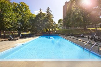 Swimming pool with chaise lounge chairs at Britannia by the Bay Apartments in Ottawa, ON