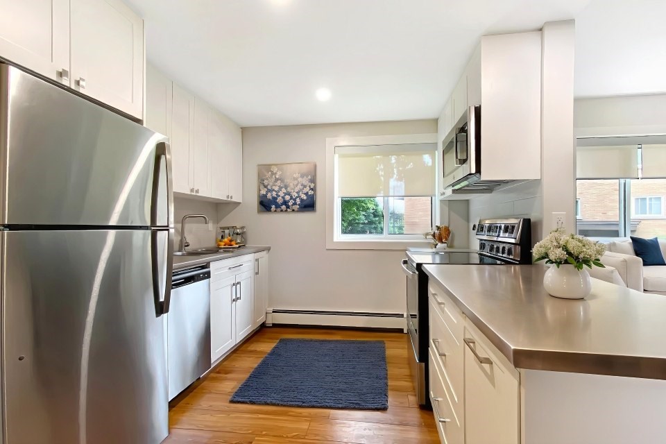 A kitchen with a stainless steel refrigerator and white cabinets.