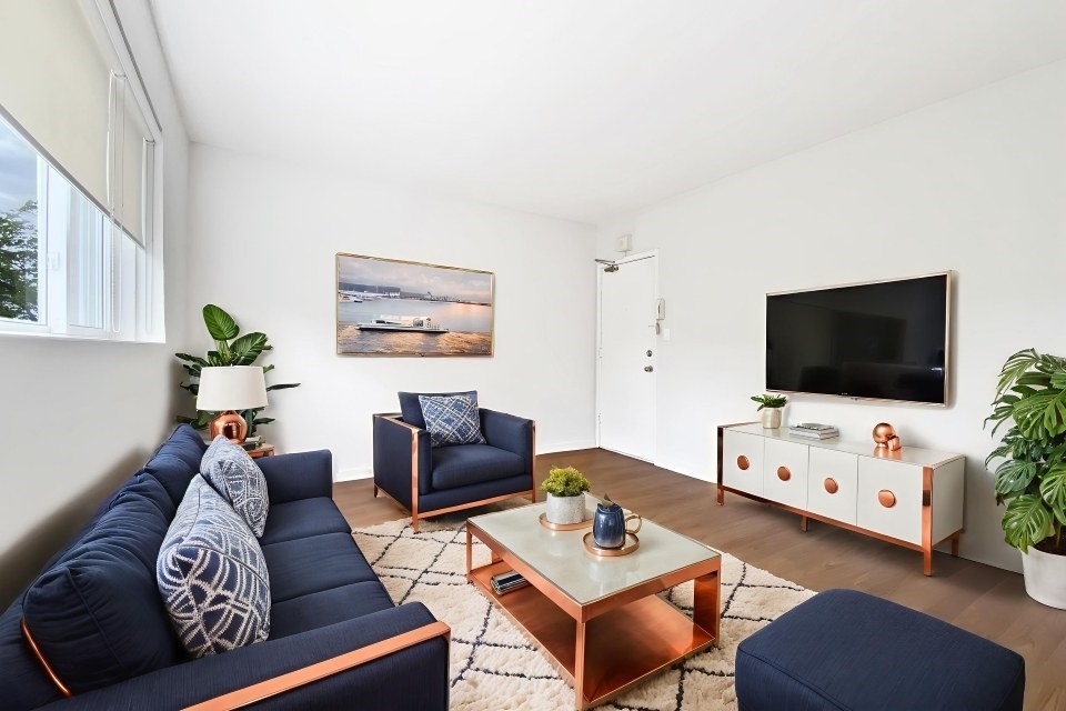 A living room with a blue sofa, a wooden coffee table, and a painting on the wall.