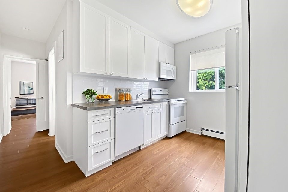 A kitchen with white cabinets and appliances.