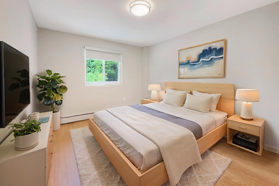 A bedroom with a bed, nightstands, and a painting on the wall.