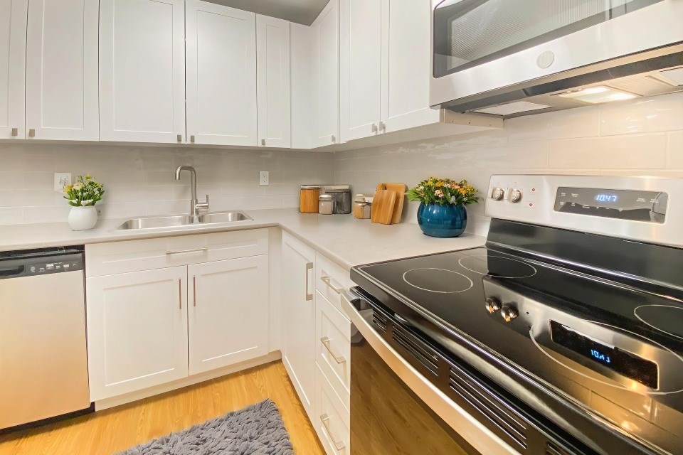 A modern kitchen with a stove top oven and white cabinets.