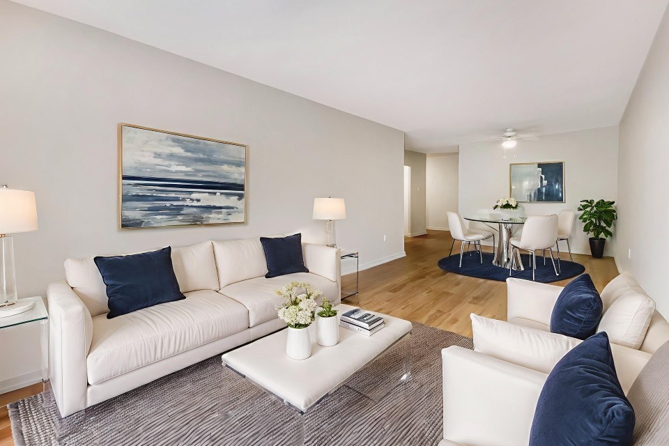 A living room with white furniture and a painting on the wall.