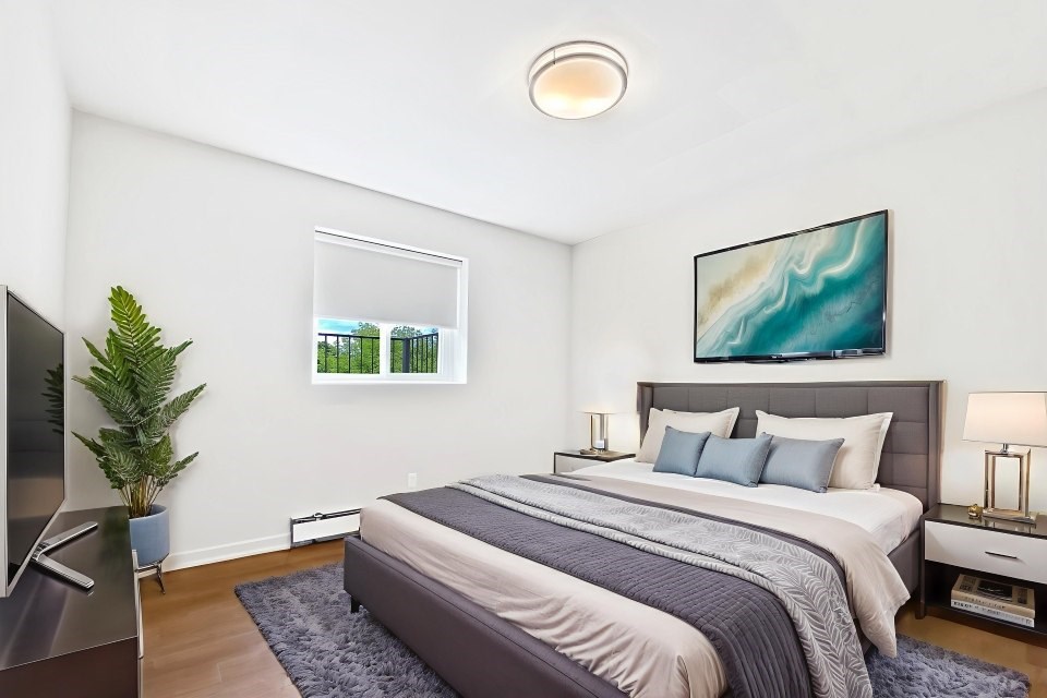 A bedroom with a large bed and a painting on the wall.