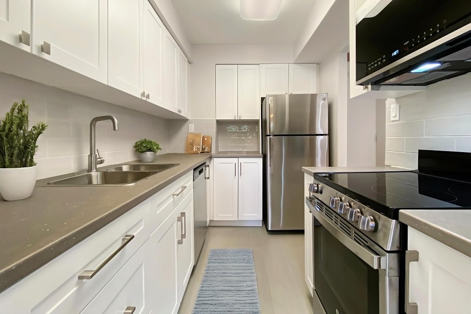 A modern kitchen with white cabinets and stainless steel appliances.