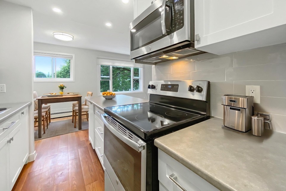 A modern kitchen with stainless steel appliances and wooden floors.