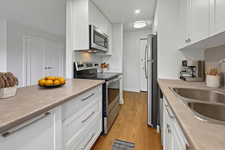 A kitchen with white cabinets and a black refrigerator.