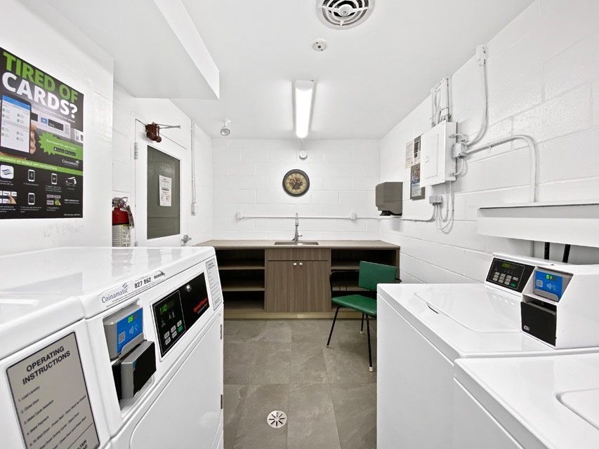 A clean, white-walled kitchen with a microwave, oven, and a clock on the wall.