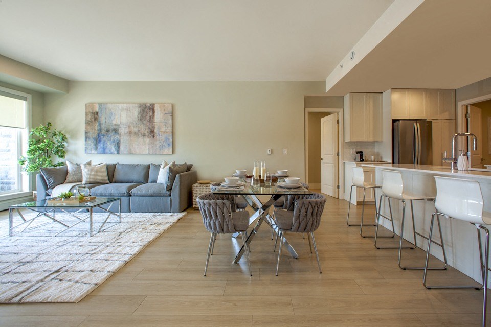 a living room with a couch a table and chairs and a kitchen with a refrigerator and a