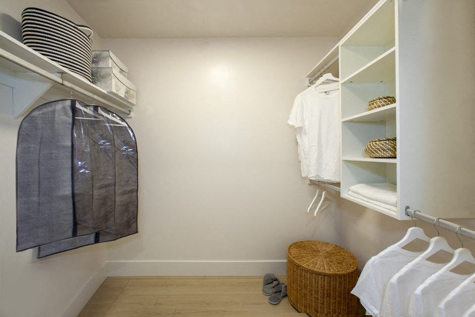 a walk in closet with white shelves and a wicker basket