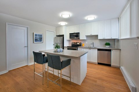 A kitchen with a white counter top and grey chairs.