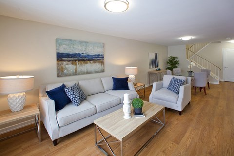 A living room with a white couch, a coffee table, and a painting on the wall.