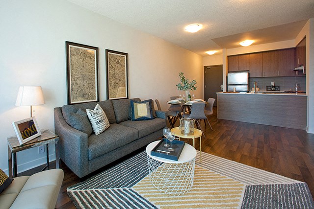 Cityview Apartments Living room with two antique paintings hanging over the grey couch in Brampton, ON