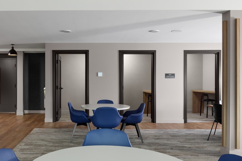 A conference room with a white table and blue chairs at The Ambrosi in Kelowna, BC.