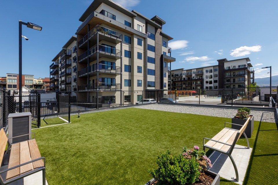 A modern building with a grassy area in front and a bench on the left side.