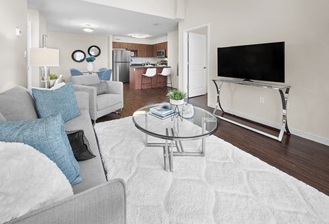 A modern living room with a grey couch and a glass coffee table.