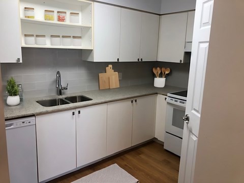 A kitchen with white cabinets and a grey backsplash.