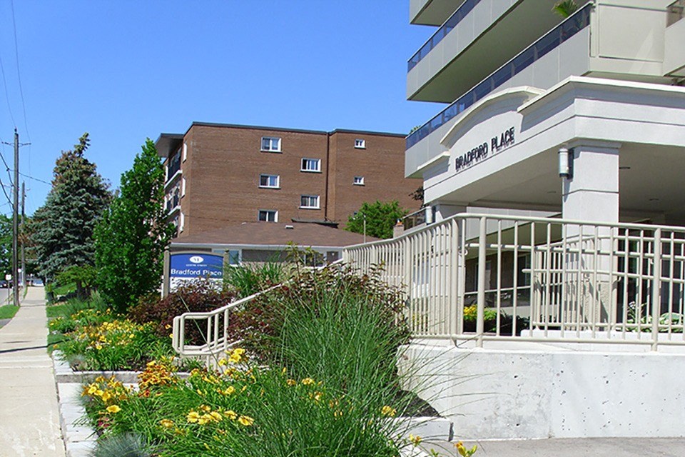 Garden with bright yellow flowers next to the main entry at Bradford Place Apartments in Bradford, ON