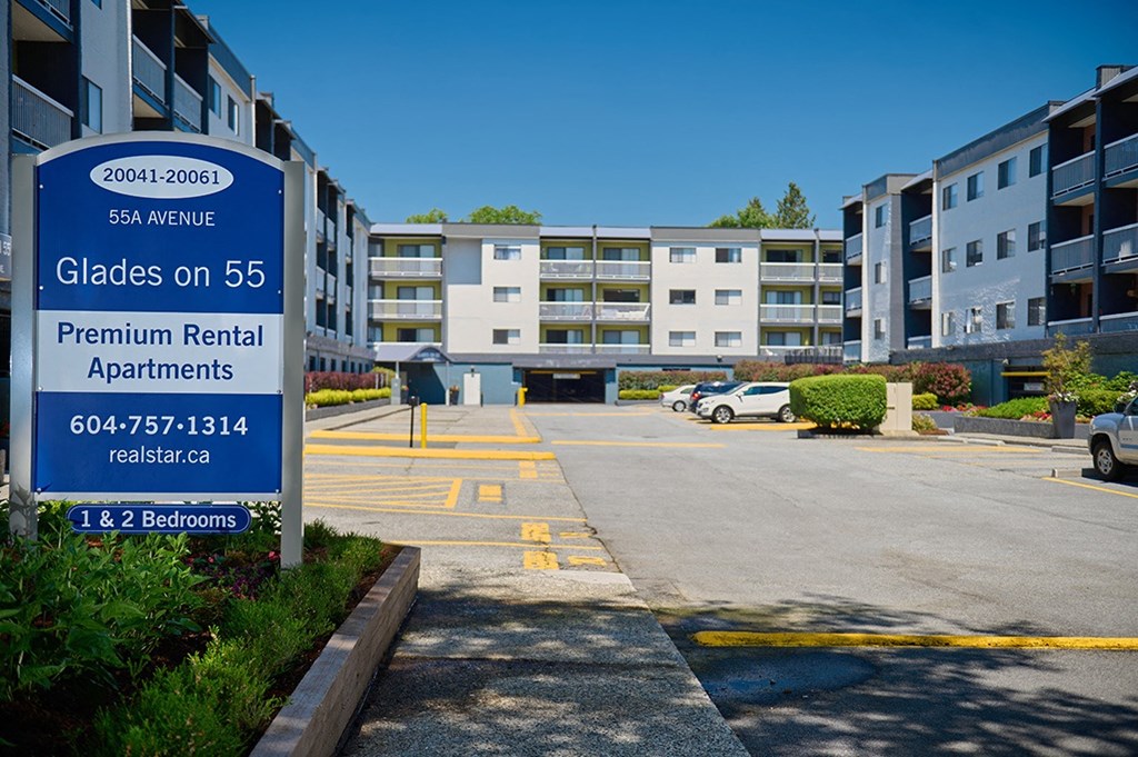 a sign for the glades on 55 apartments sits in front of a parking lot