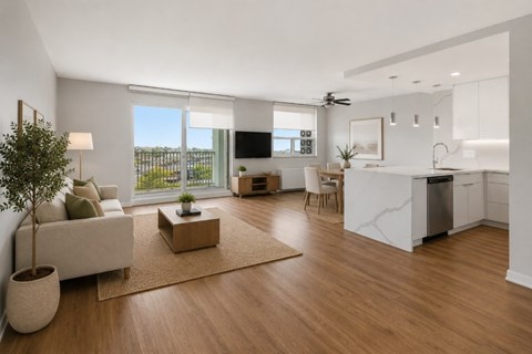 A modern living room with a white sofa, a wooden coffee table, and a large window.