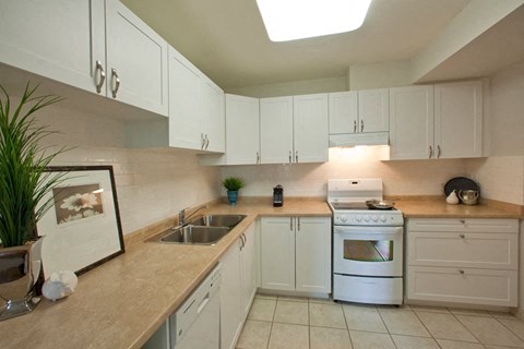 A kitchen with white cabinets and a white stove top oven.