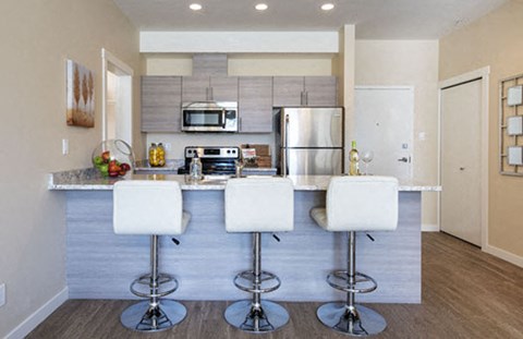 a kitchen with a bar with three chairs