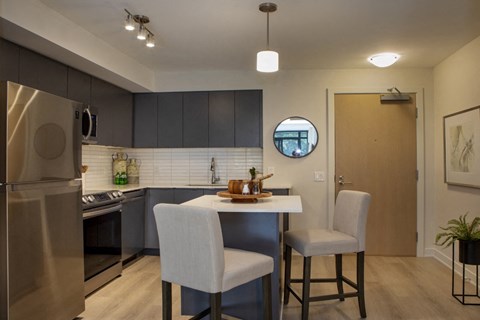 a kitchen and dining area with a stainless steel refrigerator and a table with two chairs