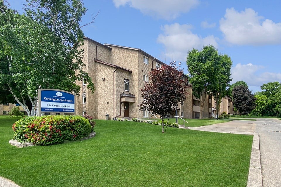 Kensington Apartments in Brockville Ontario showing a blue and white community sign and building in the background