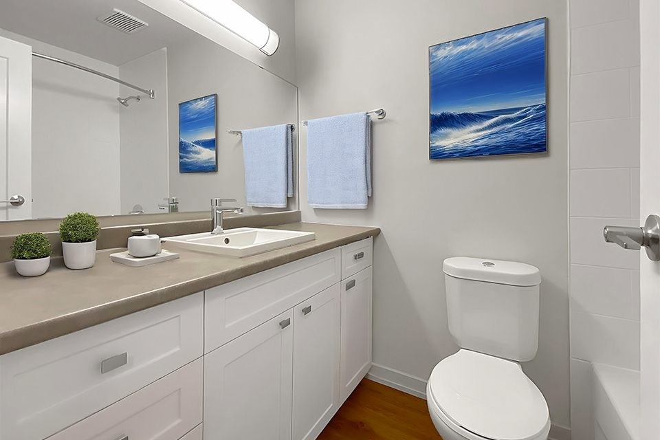 A bathroom with a white toilet, a sink, and a mirror.