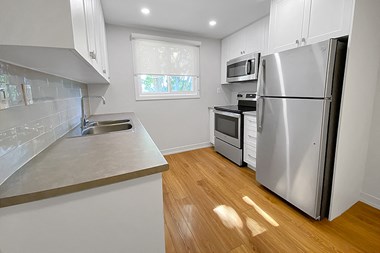 Kensington Apartments in Brockville partially open concept kitchen with stainless steel fridge, stove and OTR microwave