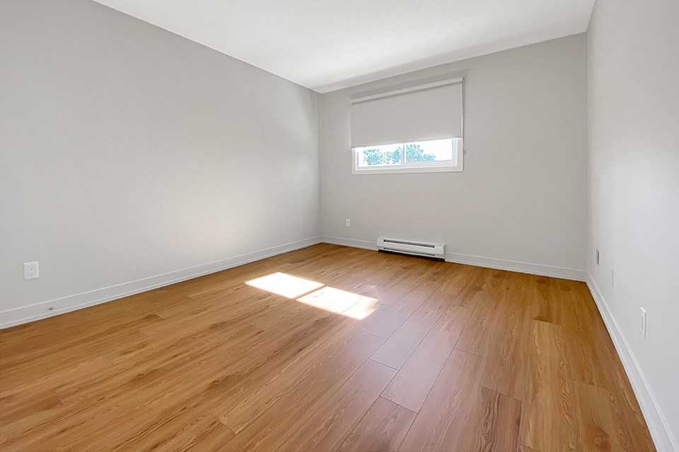 Kensington Apartments primary bedroom from doorway looking toward window with blackout blinds