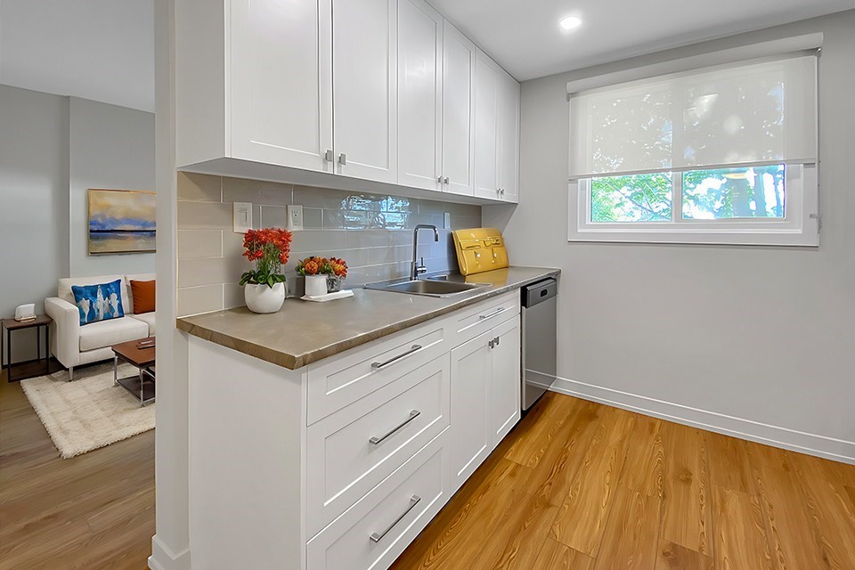 A kitchen with white cabinets and a wooden floor.